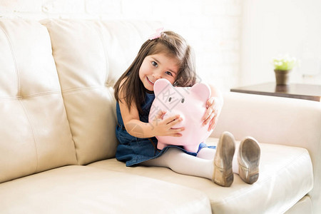 小女孩坐在客厅沙发上时抱着图片