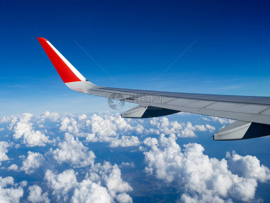 从乘客美丽的云团和蓝天的飞机窗看飞行期间在高度上的机翼飞机旅行和商务旅行的概念图片