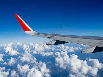 从乘客美丽的云团和蓝天的飞机窗看飞行期间在高度上的机翼飞机旅行和商务旅行的概念背景图片