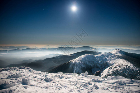 寒冬山脉的分布范围夜晚白雪中夜深蓝天空下背景图片