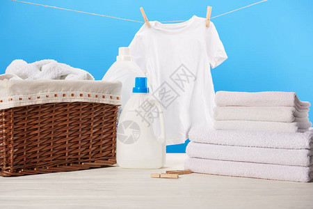 蓝色绳子上挂着洗衣液洗衣篮毛巾堆和干净的白色衣图片
