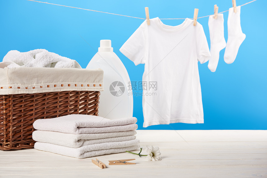 洗衣篮装有洗衣液的塑料容器一堆干净的软毛巾和挂在蓝色晾衣绳图片