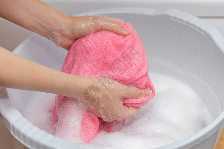 灰色塑料盆地的妇女洗手毛衣洗大量肥皂白色洗涤剂干图片