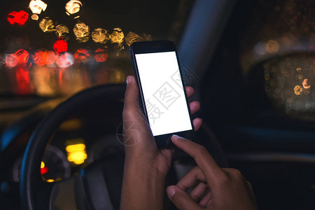 城市夜晚在车内使用手机的特写手图片