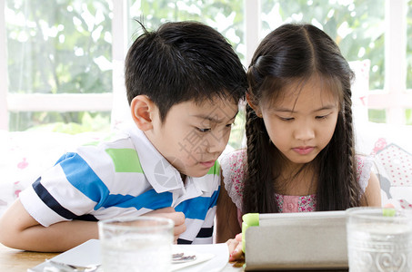 小亚洲微笑女孩和男孩与平板电脑图片