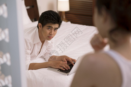 年轻亚洲男子在笔记本电脑上打字和图片