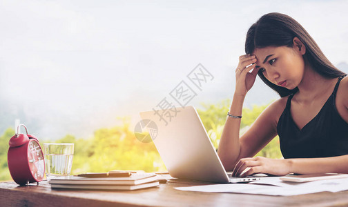 女人一边用笔记本电脑一边担心自己的工作赶不上最后期限图片