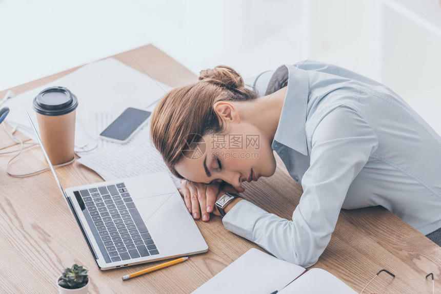 成年女商人在工作场所睡觉已精疲力图片
