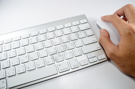 在白色键盘附近手动操作白色鼠标图片