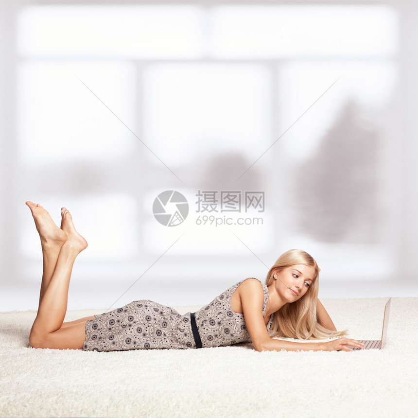 穿着白色全楼地毯的金发年轻女子在窗户旁浏图片