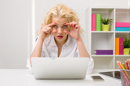 办公室里疲倦的女人看着电脑睁着眼睛背景图片