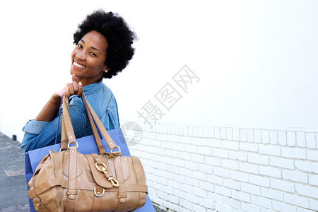 一个微笑的年轻女人背着袋子走来图片