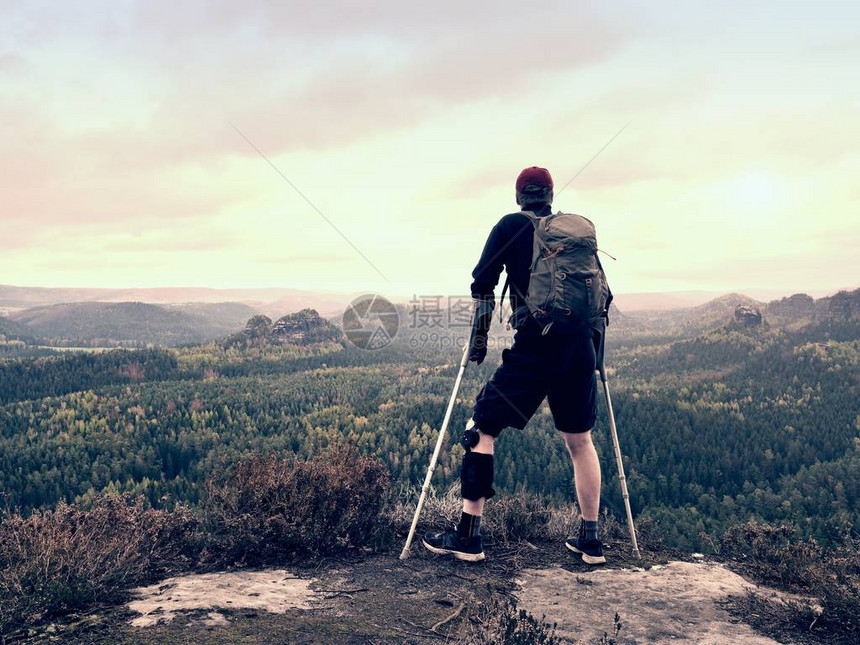 在岩石上拐杖上的残疾旅游者图片