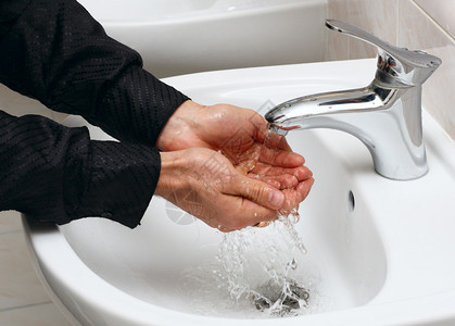 男人在公共厕所里用自来水洗手图片