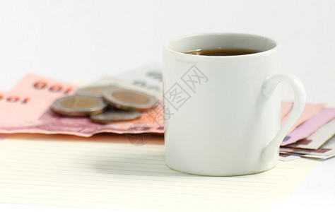 咖啡杯和钱在白背景图片