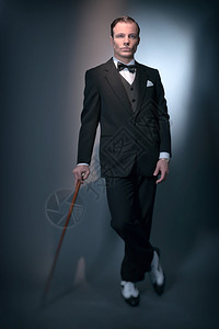Retro1920商业时装男身着黑色西装和领结手持拐杖图片