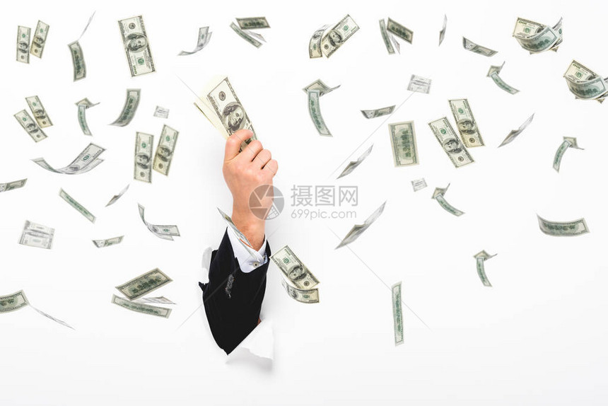 男子通过白色纸墙上的洞拿着钱的剪影上图片