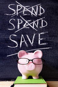 在黑板旁边的书上站着眼镜的粉红小猪银行图片