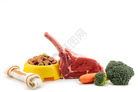 白色背景中的一碗狗粮骨头零食肉胡萝卜和西兰花图片