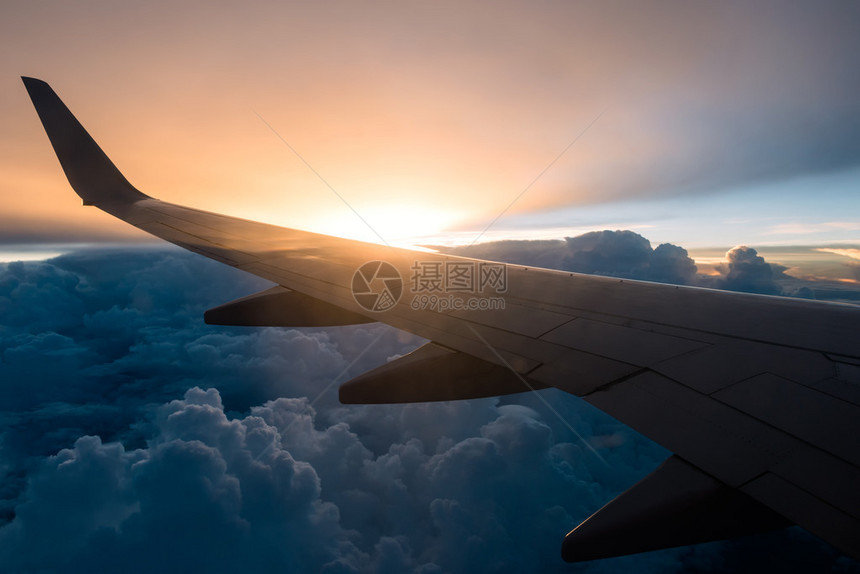 日落背景和云上的飞机翼图片