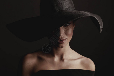 深色工作室肖像优雅感女人穿黑色大帽子和黑裙背景图片