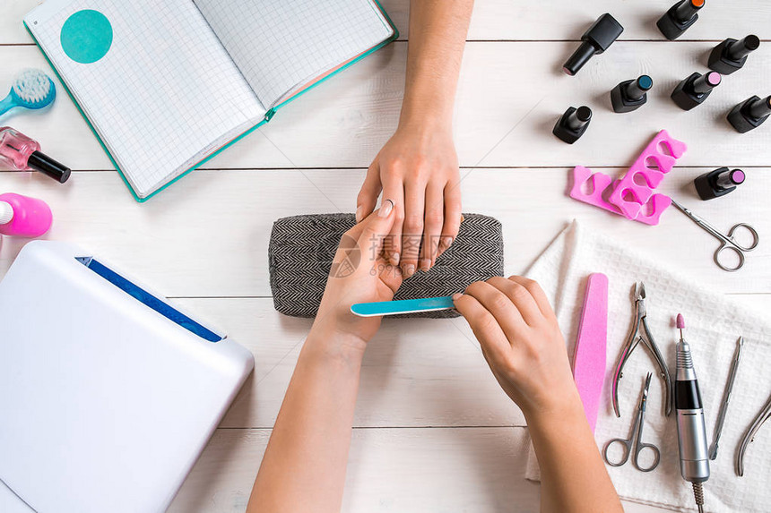 指甲护理在甲沙龙用专业指甲锉指甲的女手的特写师手在女人手上做完美修指甲的特写镜头指甲图片