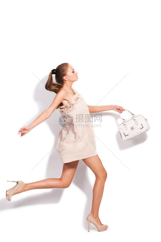 穿着优雅短裙和高跟鞋的高跟鞋的年轻女子携带手提袋跑步图片