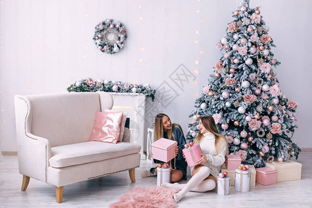 微笑的年轻女在家中美丽的圣诞树旁打开礼品盒圣诞节和的礼物带壁炉和沙图片