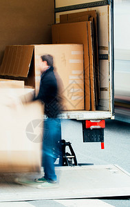 男子在街道中间用手从卡车上卸下箱子快速图片