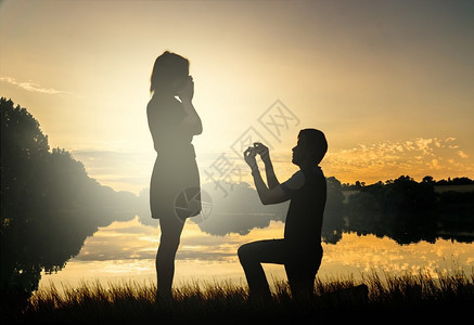 求婚概念年轻夫妇在日落时分约会恋爱中的男人跪在地上图片