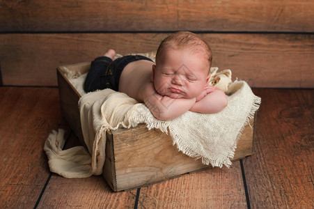 工作室肖像一个月大的新生儿男孩穿着牛仔裤睡图片