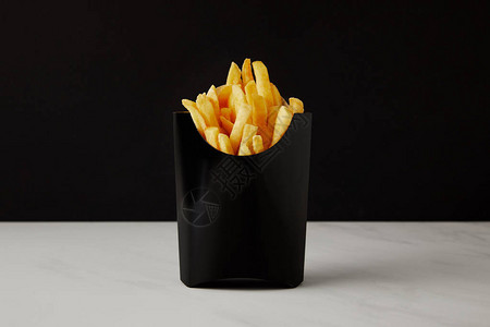 白色大理石表面上的薯条盒与黑色隔开背景图片
