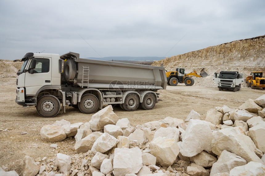 StonePit中的重型卡车和推土机专注于前卡车前大石块和黄色推土图片