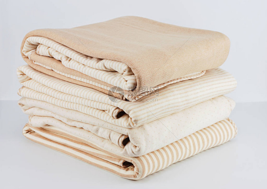 白背景新生儿用堆叠成的天然蜜蜂棉毯包装在白色背图片