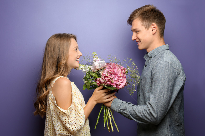 年轻男人用彩色背景给心爱的女朋友送鲜花图片