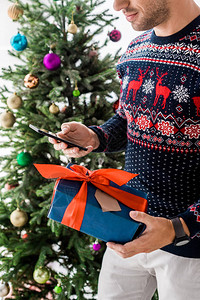 带礼物盒和智能手机的圣诞节毛衣上图片