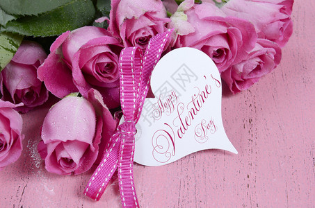 粉红玫瑰在粉红色木头背景上与情人节快乐的图片
