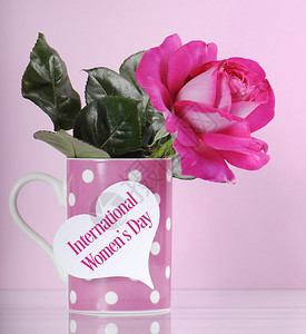 快乐的国际妇女节问候与粉红色的玫瑰和圆点咖啡杯在粉红色的背图片