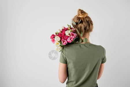 女孩拿着带郁金香和玫瑰的新花束在灰色与图片