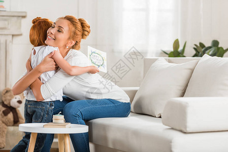 带着贺卡手抱着彼此拥抱的母亲和女儿笑着微笑图片