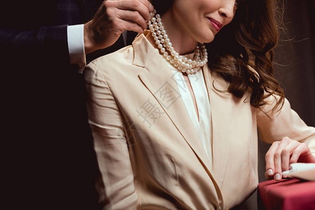 将珍珠项链戴在微笑的女人身图片
