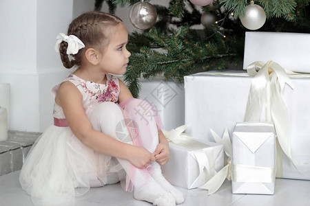 周到的小女孩坐在装饰精美的新年树下的肖像图片