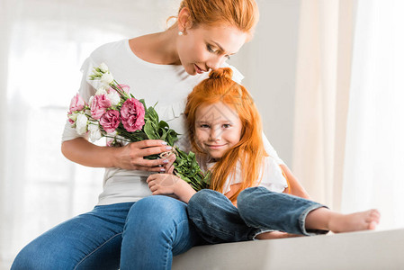 带着一束鲜花拥抱着小女儿在家的母亲微笑的母亲图片