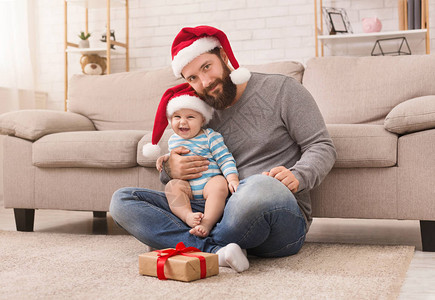 圣诞快乐快乐父亲和他的小宝戴着圣塔帽玩得开心图片
