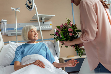 送花给医院里快乐的年长妇女图片
