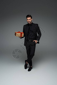 正式黑西装男子持有灰色礼品盒图片