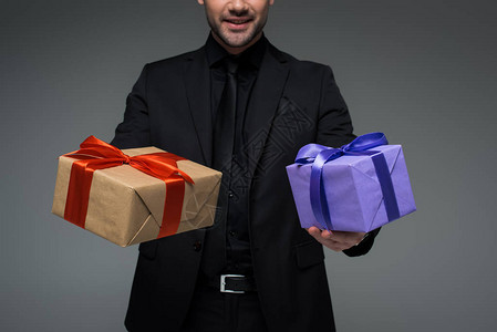 穿着黑色西装的男拿着两个礼品盒的剪影图片