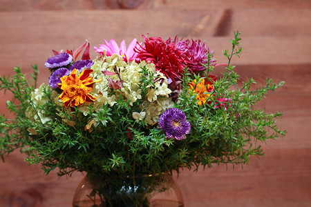 深色木质背景上带鲜花束的玻璃花瓶背景图片