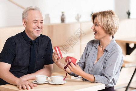 男人在咖啡馆向女人赠送一个红色礼盒图片