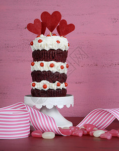 新奇的三层红色天鹅绒纸杯蛋糕放在白色蛋糕架上图片